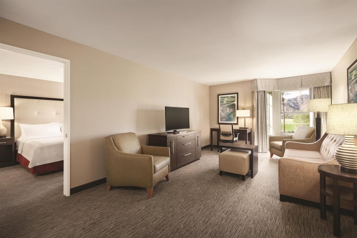 Une chambre d’hôtel comprenant un lit, une télévision, un bureau avec une chaise, un canapé et une lampe.