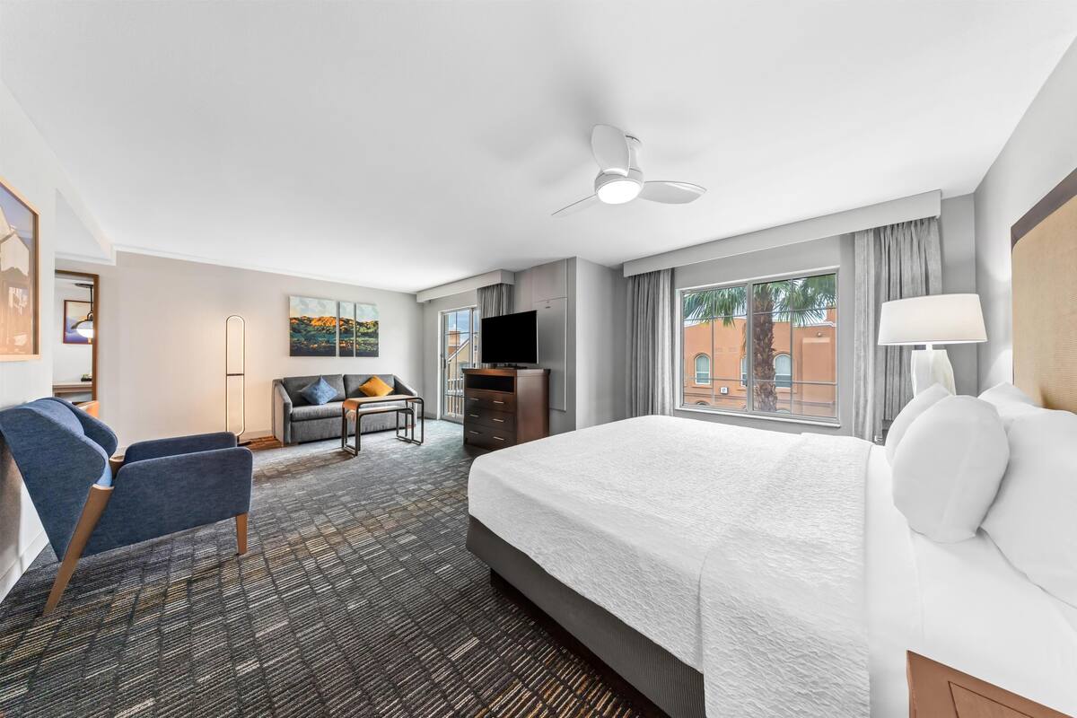 Une chambre d’hôtel avec un grand lit, un bureau, une chaise, une télévision et une vue sur l’extérieur.