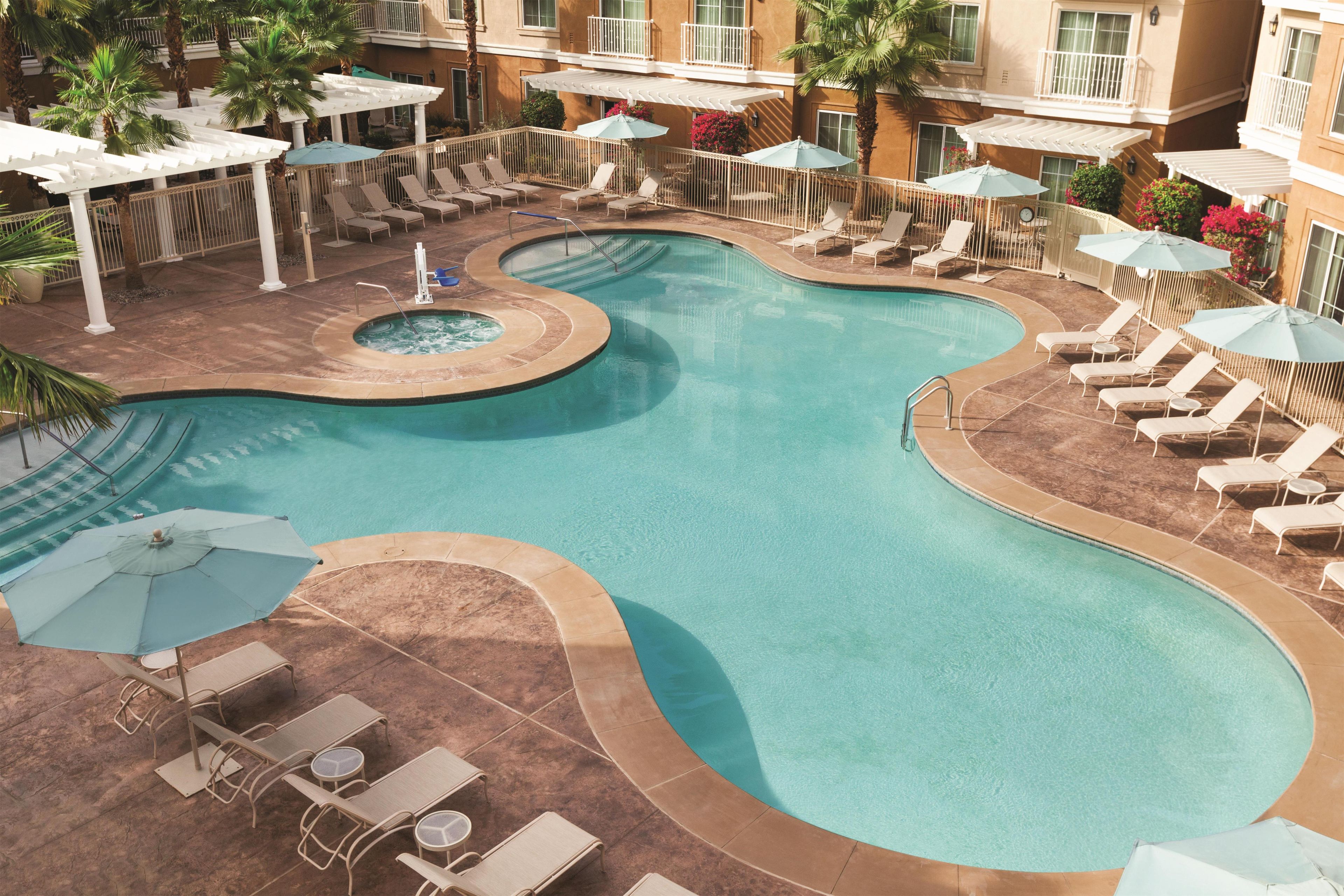 A pool area with lounge chairs and umbrellas.