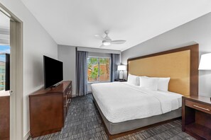 Une chambre d’hôtel équipée d’un lit, d’un téléviseur à écran plat, d’un ventilateur de plafond et d’une fenêtre avec des rideaux.