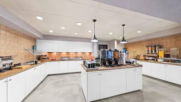 A modern kitchen with a central island, built-in appliances, and a variety of food dispensers.
