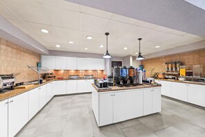 Una cocina moderna con una isla central, electrodomésticos integrados y diferentes dispensadores de alimentos.