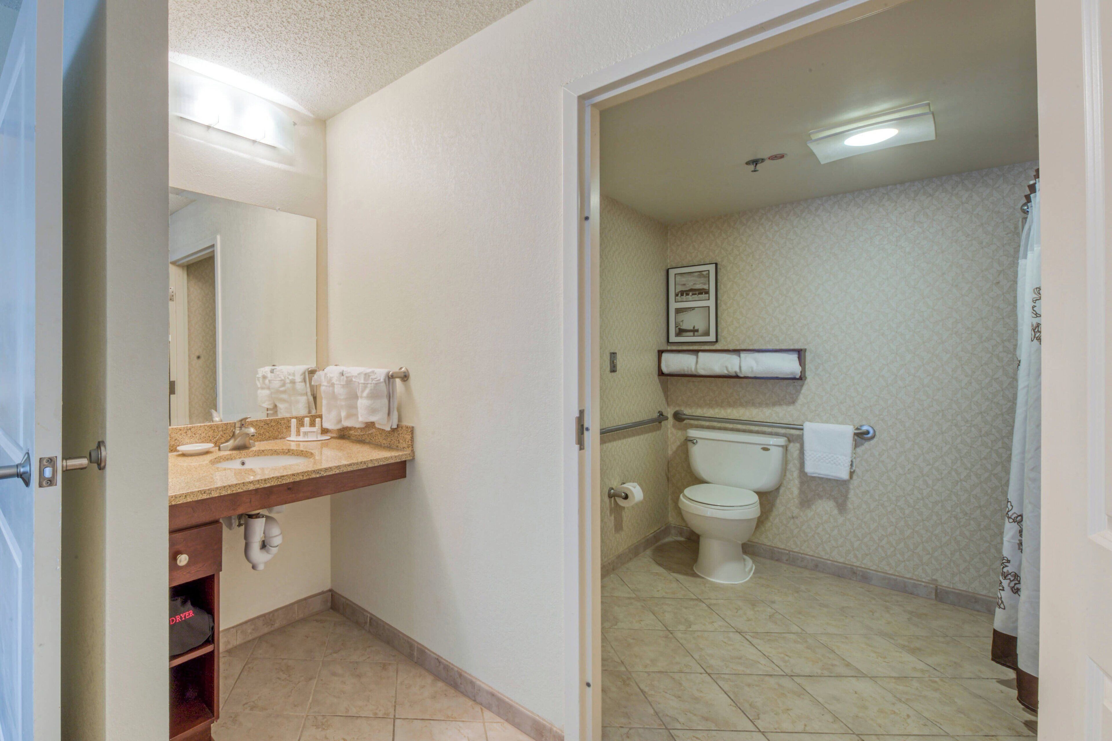 A bathroom with a double sink, toilet, and a shower area.