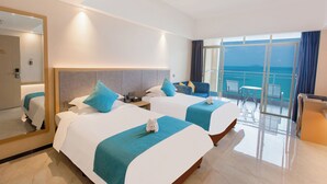 Ein Hotelzimmer mit zwei Betten, einem Balkon mit Blick und einer Sitzecke.