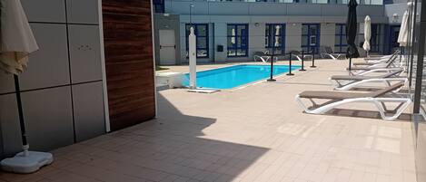 Un área junto a la piscina con sillones de descanso y una piscina pequeña.