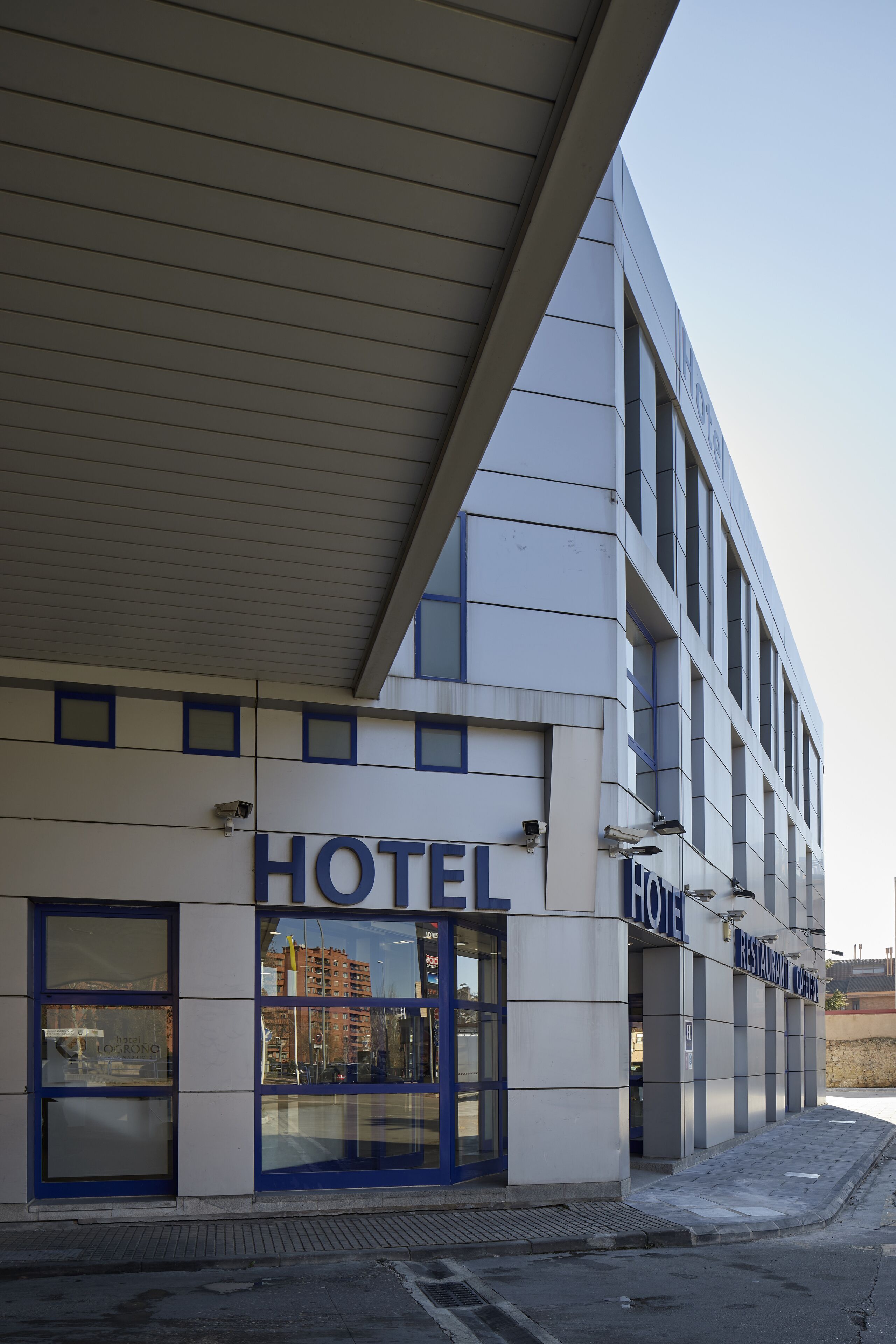 Un hotel con fachada moderna, amplios ventanales de vidrio y un letrero destacado que dice 