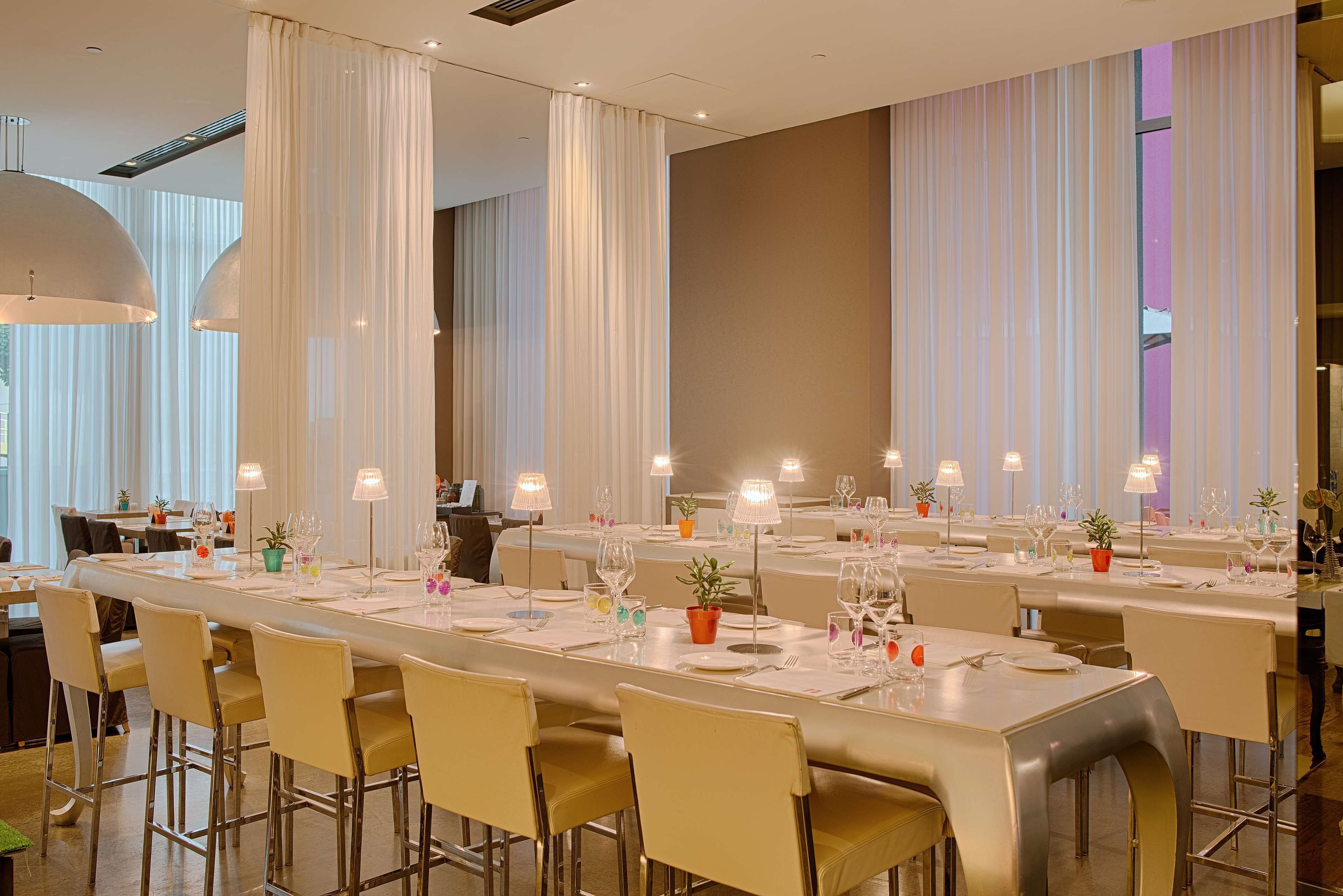 A modern dining area with long tables, chairs, and ambient lighting.