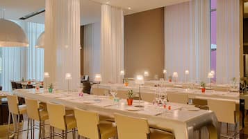 A modern dining area with long tables, chairs, and ambient lighting.