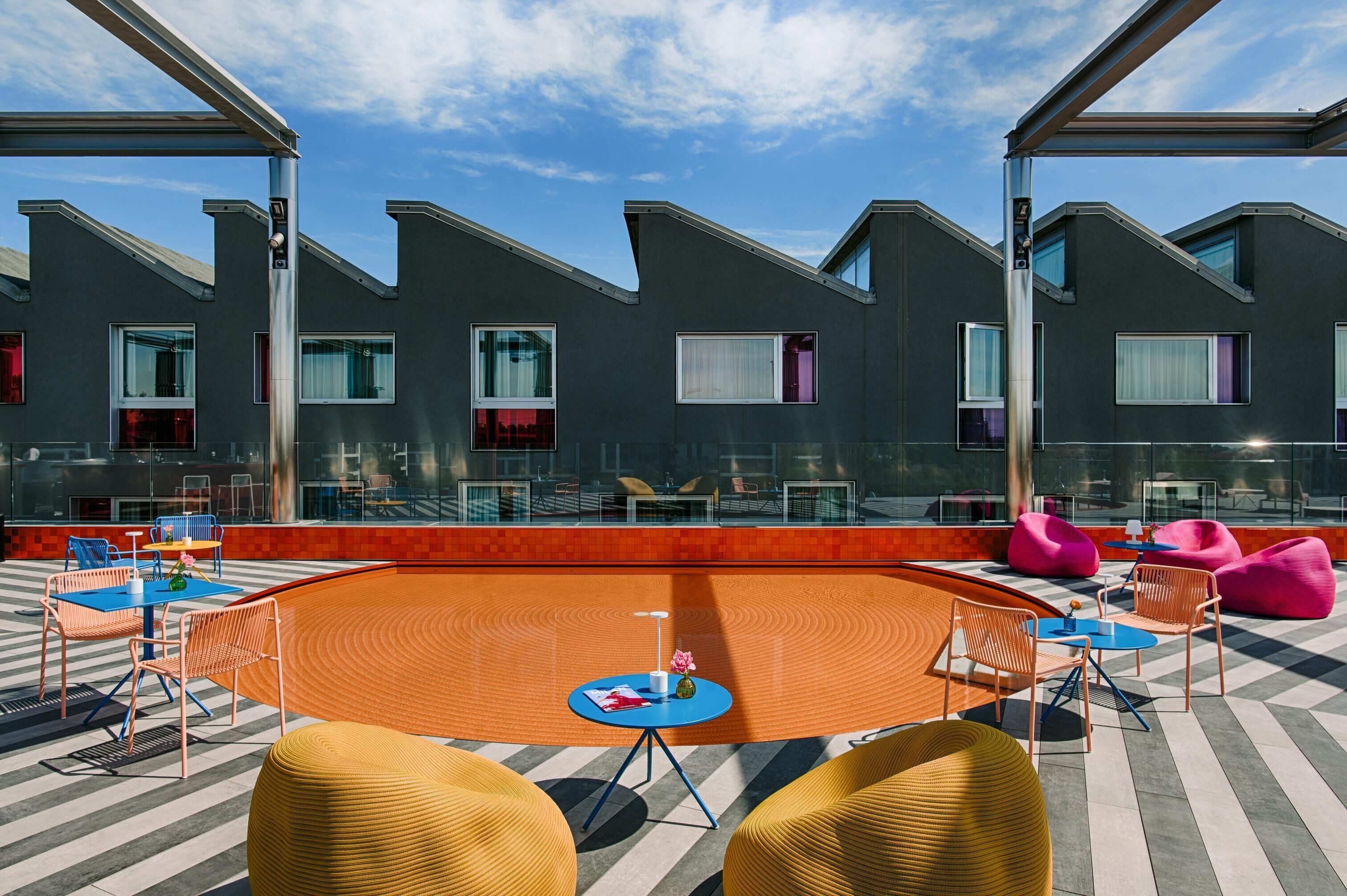 A rooftop terrace with a circular seating area, multiple tables, and chairs.