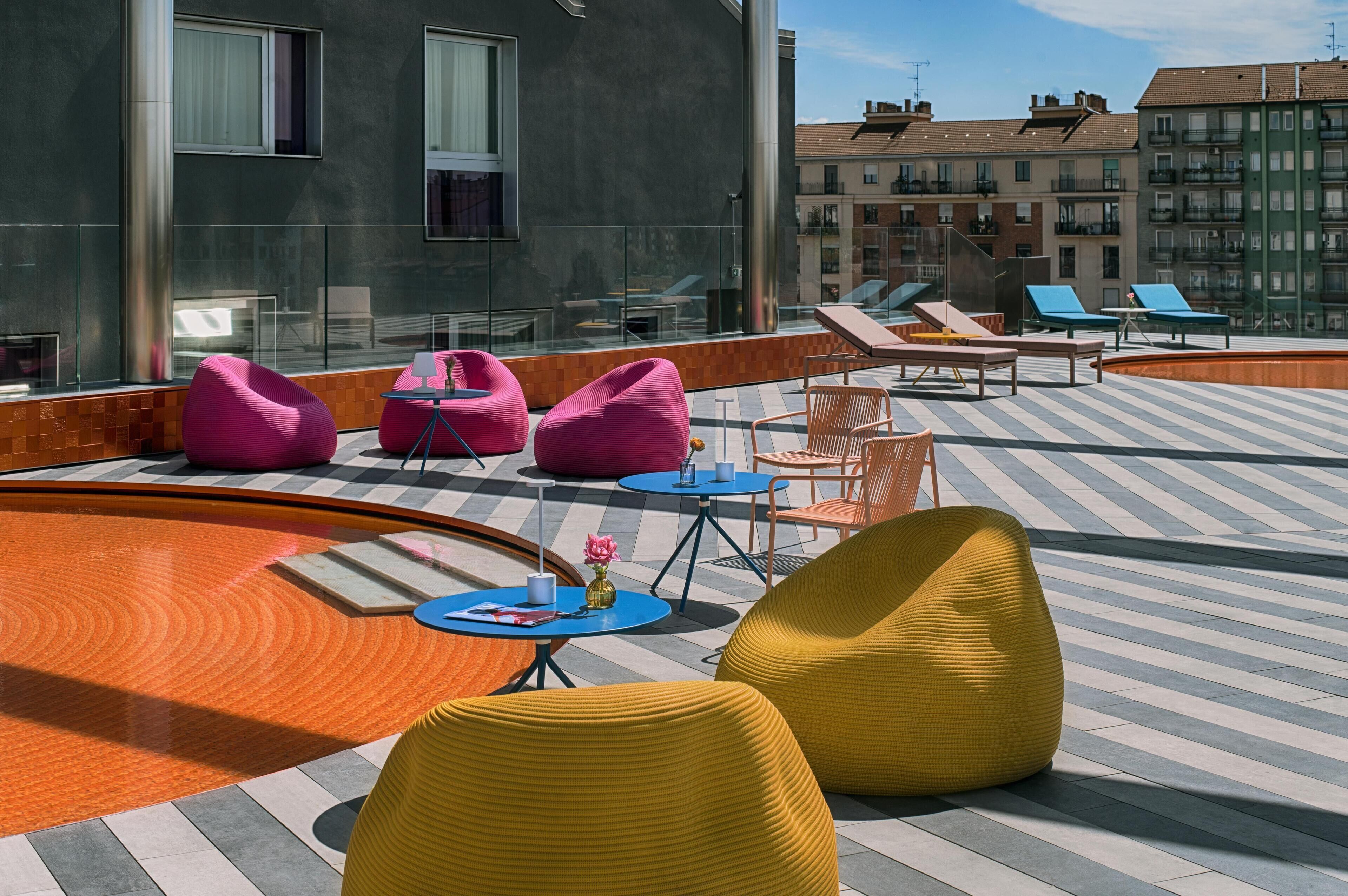 Terraza en la azotea con zonas de estar, piscina y vistas de los edificios circundantes.