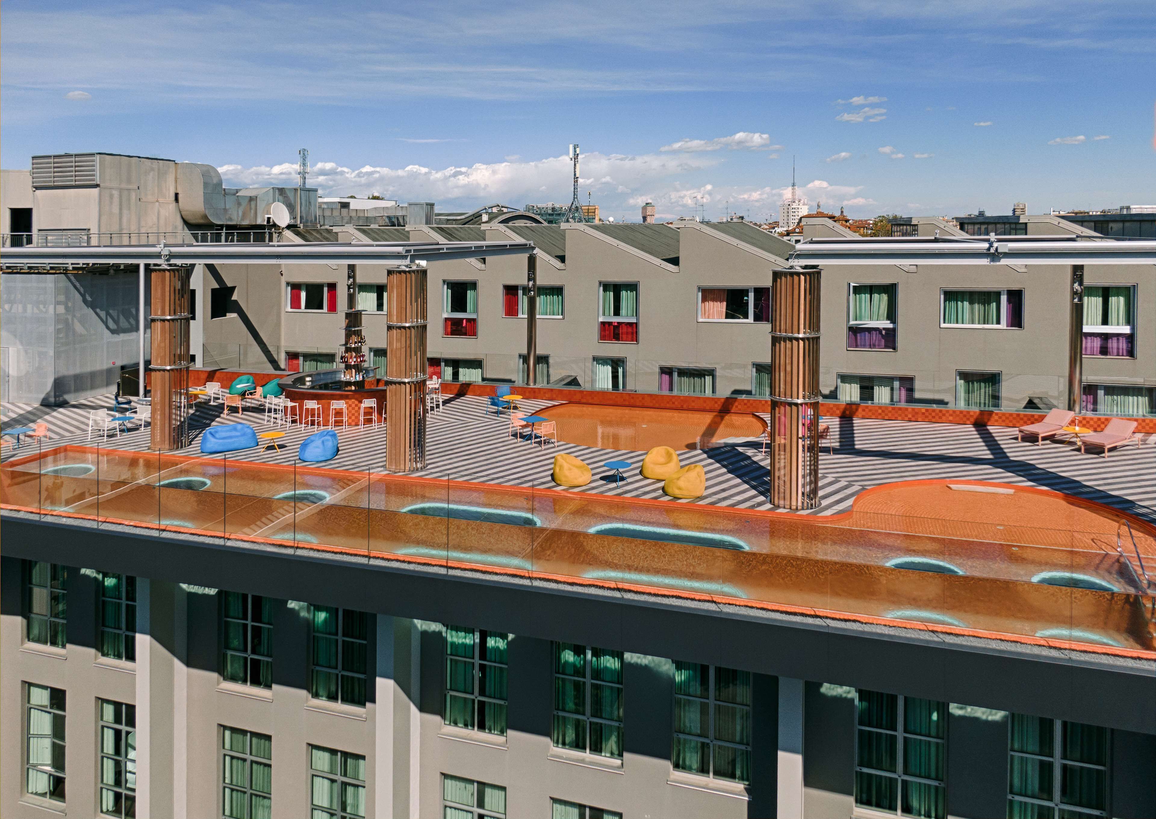 A rooftop terrace with seating areas, a pool, and a view of surrounding buildings.