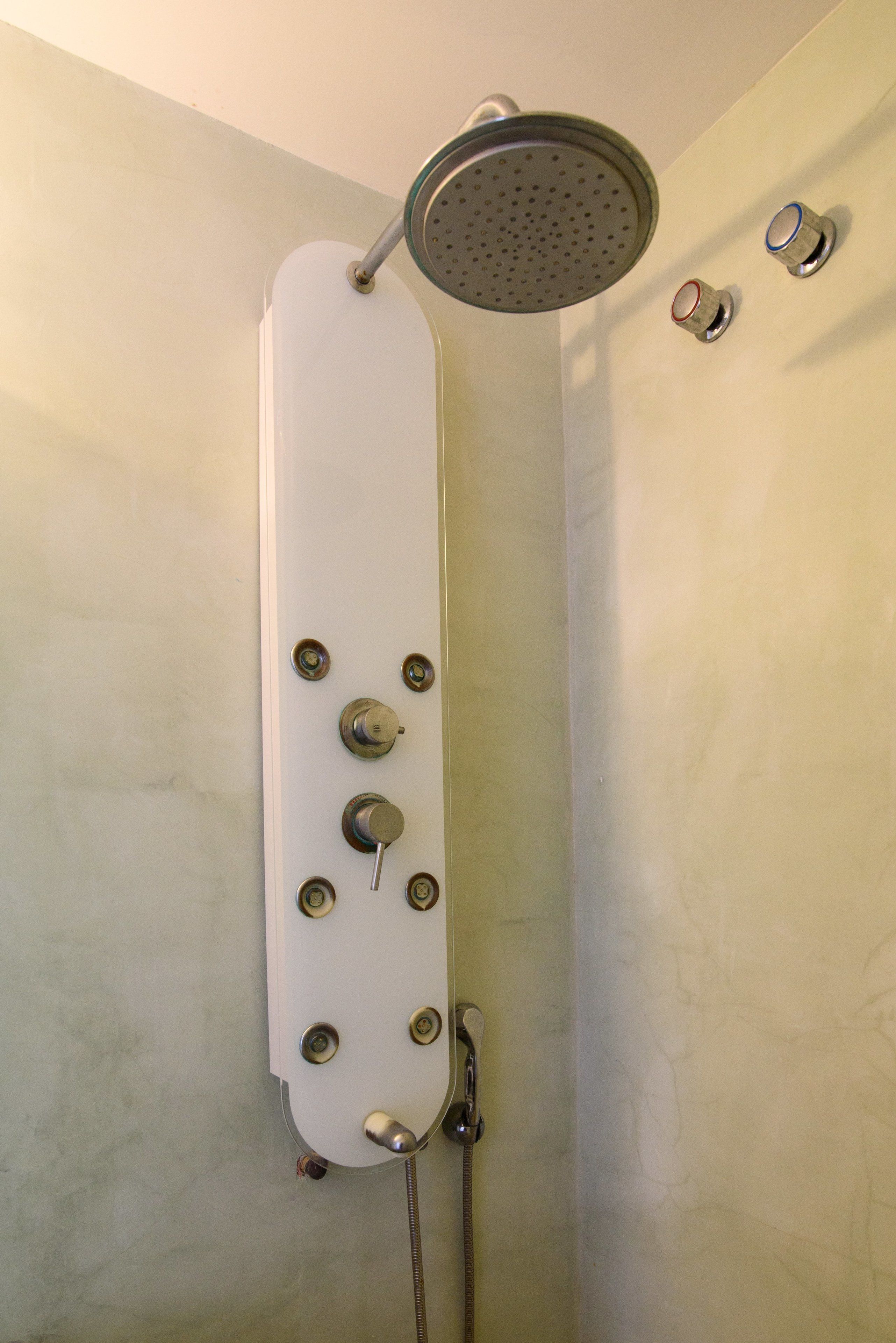 A shower with a handheld showerhead and a wall-mounted rain showerhead.