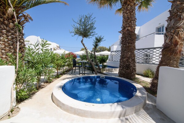 A swimming pool surrounded by palm trees and white buildings. - RK Beach Hotel (Santorini)
