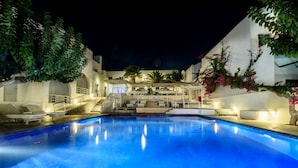 Una piscina amb vistes a un edifici amb diversos balcons i escales que condueixen a una terrassa.