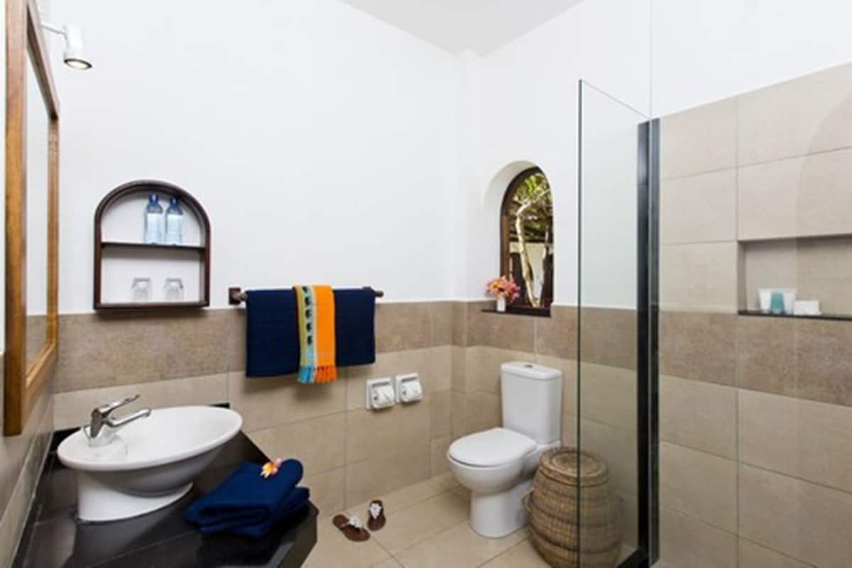 Casa de banho com lavatório, sanita e zona de duche.