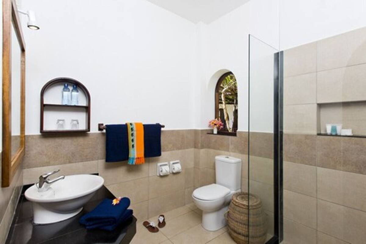 Un baño con lavamanos, inodoro y zona de ducha.
