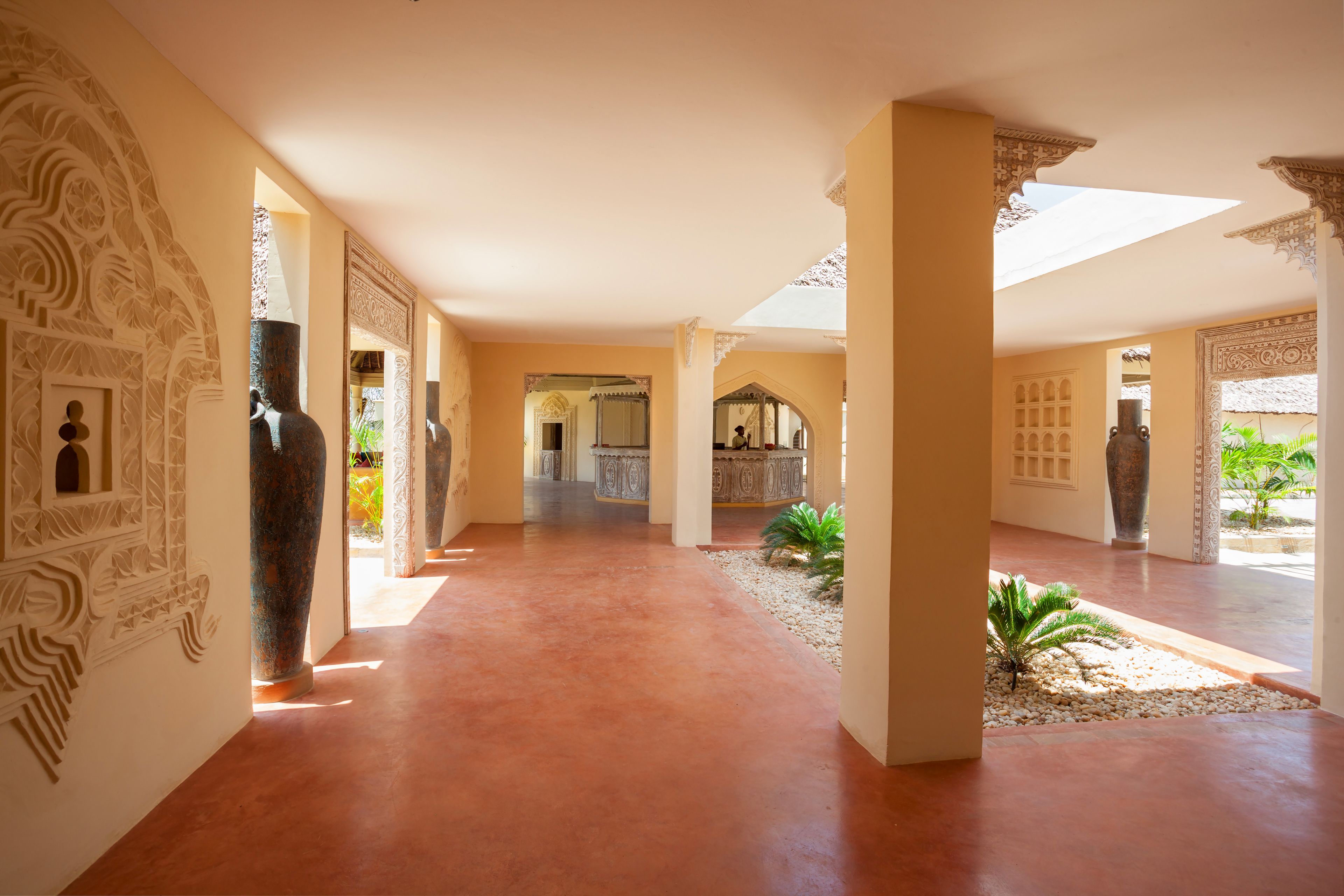 A corridor with patterned walls, large vases, and a tiled floor.