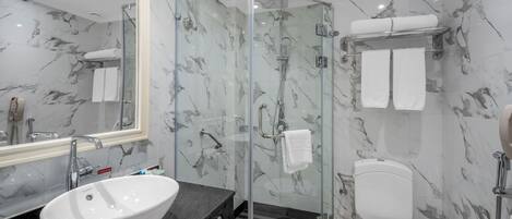 A modern bathroom with a glass-enclosed shower, a white sink, and a toilet.