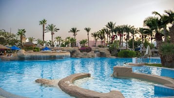 Ein großer Pool im Freien mit Felsformationen und Palmen.