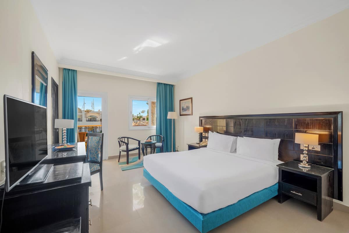A hotel room with a bed, a TV, a desk, and a chair.