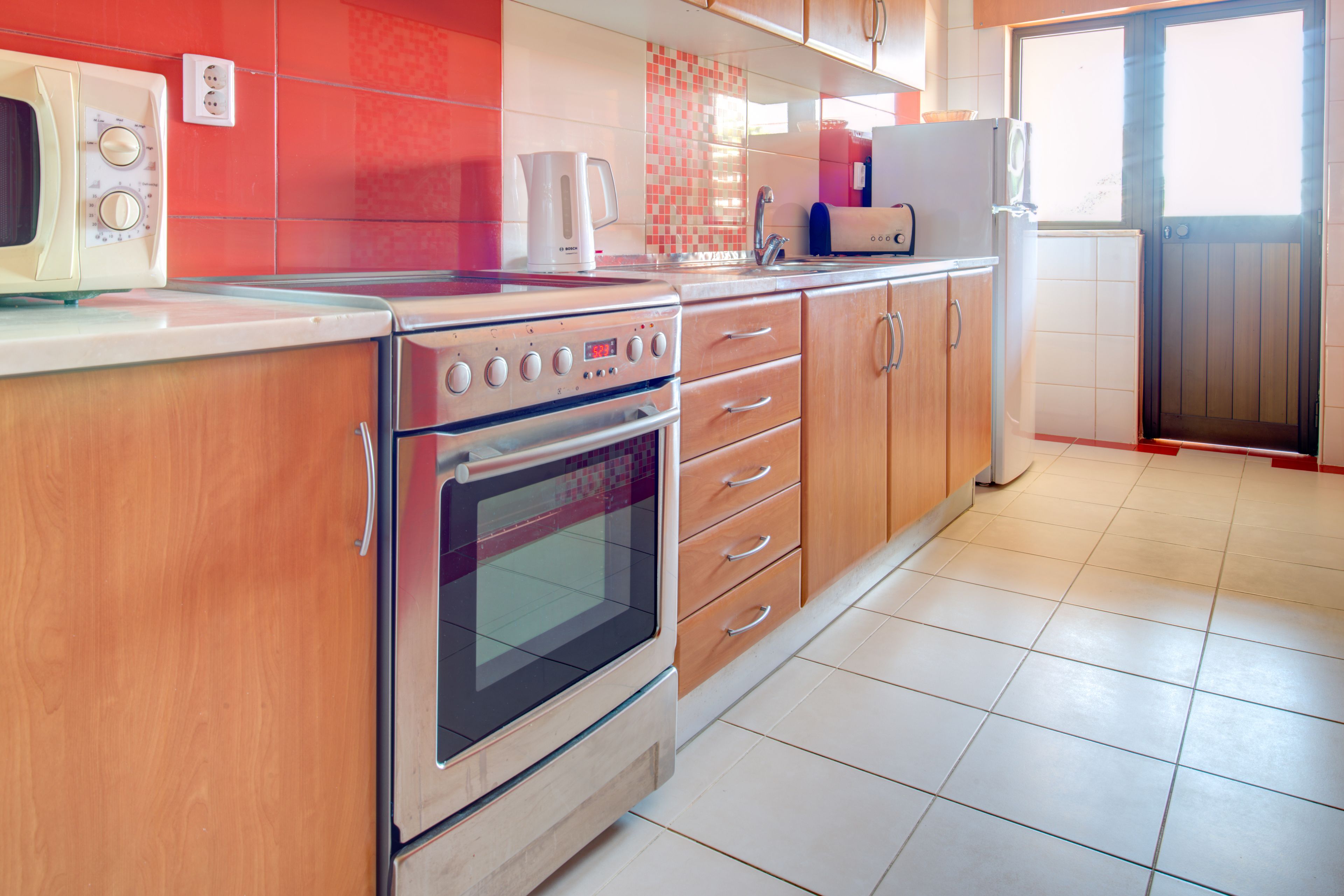 Eine Küche mit Herd, Backofen, Schränken und Kühlschrank.