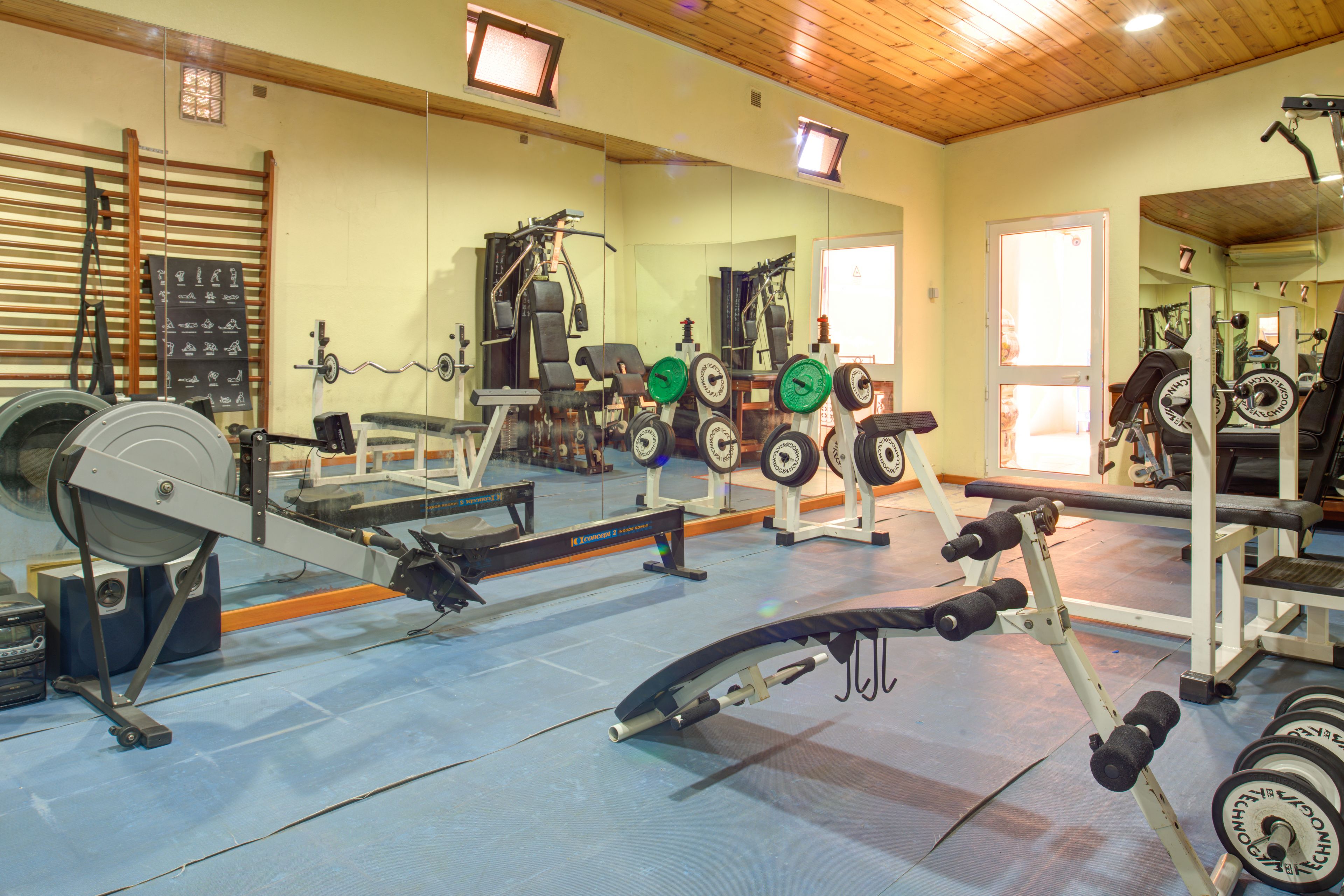 Ein Fitnessstudio mit verschiedenen Trainingsgeräten, darunter Kraftgeräte, Kurzhanteln und Cardiogeräte.