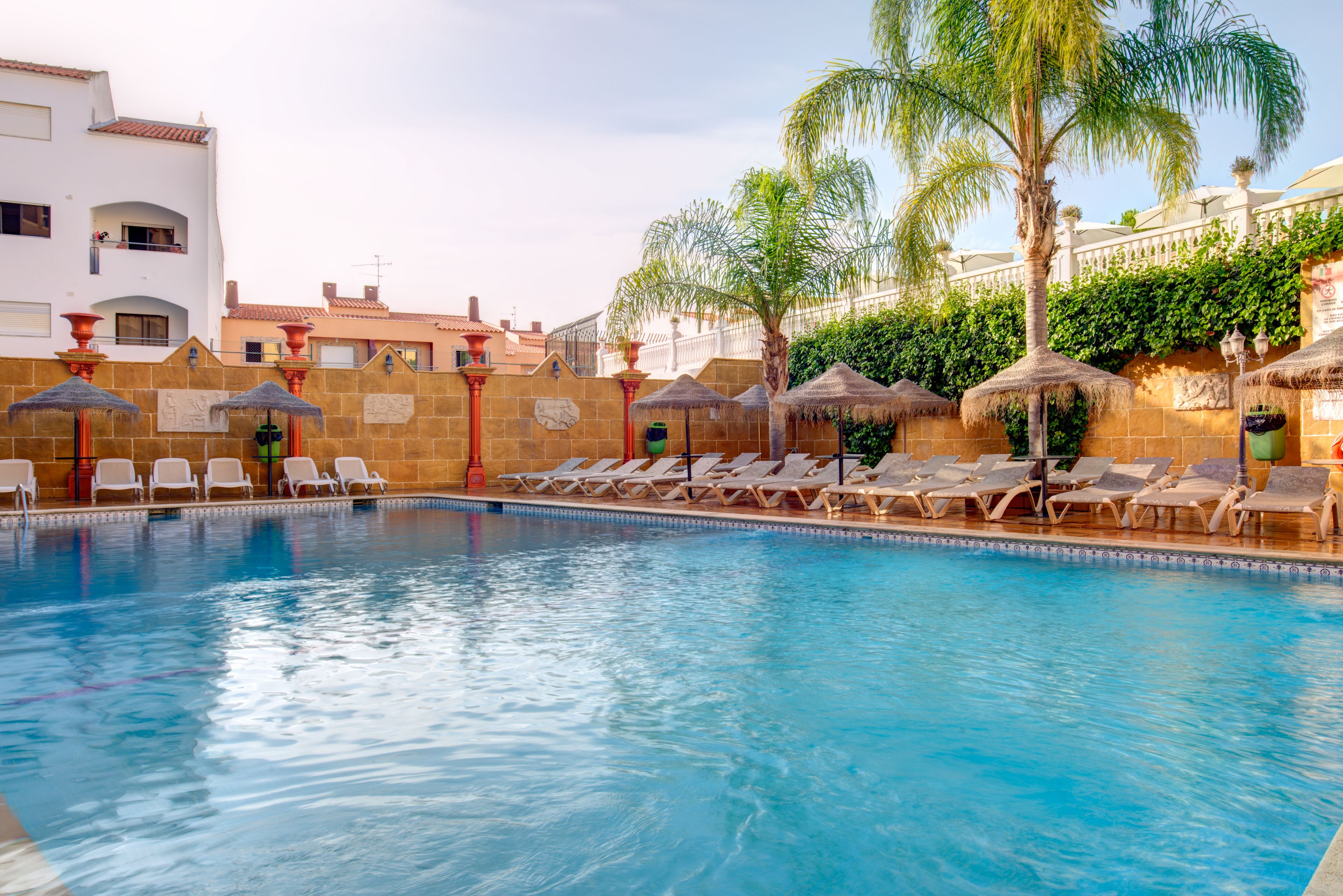 A swimming pool with lounge chairs and palm trees.