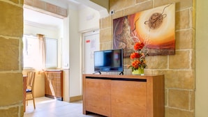 Un mueble de madera con un televisor de pantalla plana y un jarrón de flores frente a una pared de piedra.