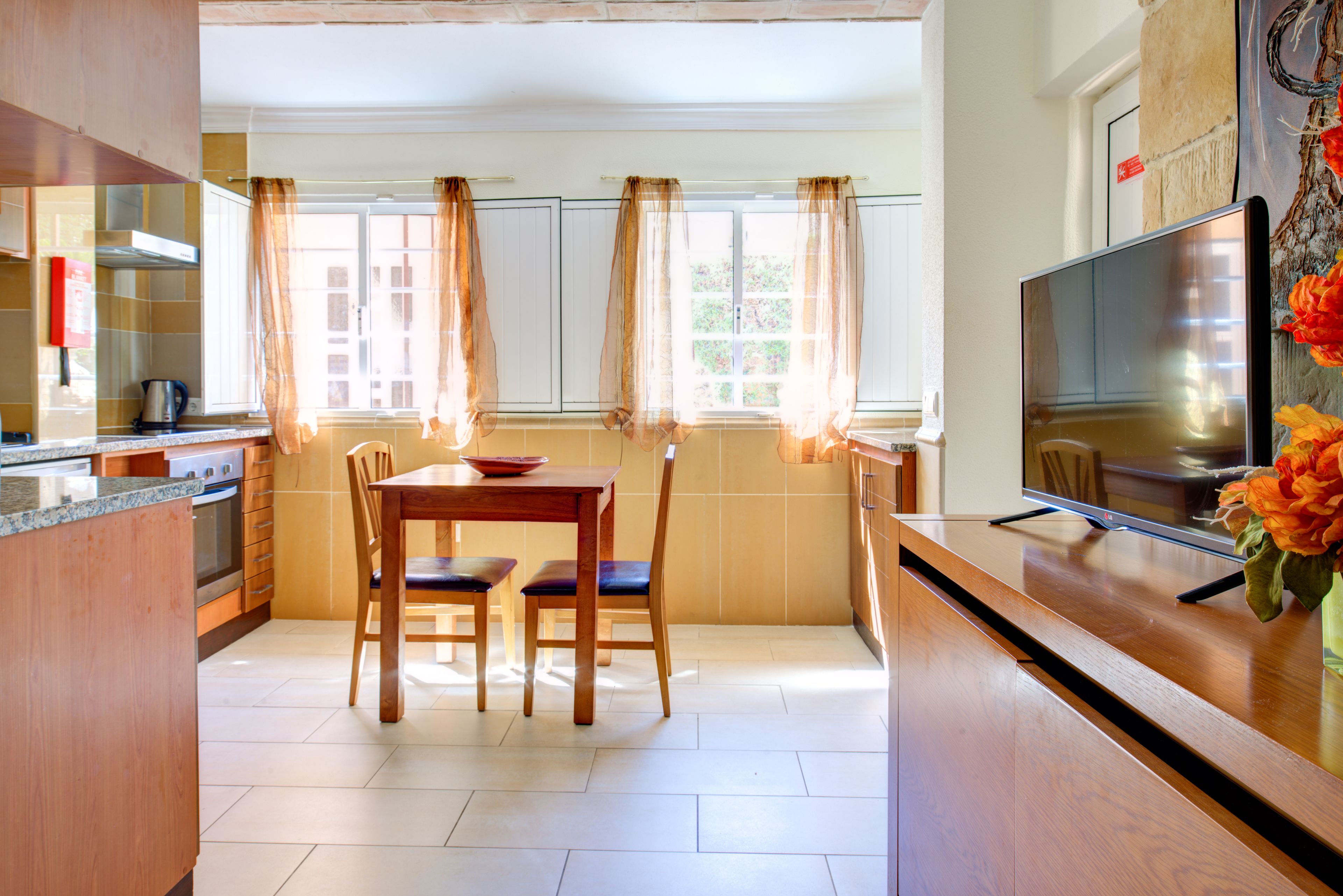 A modern kitchen with a dining area, a television, and a view of the outdoors.