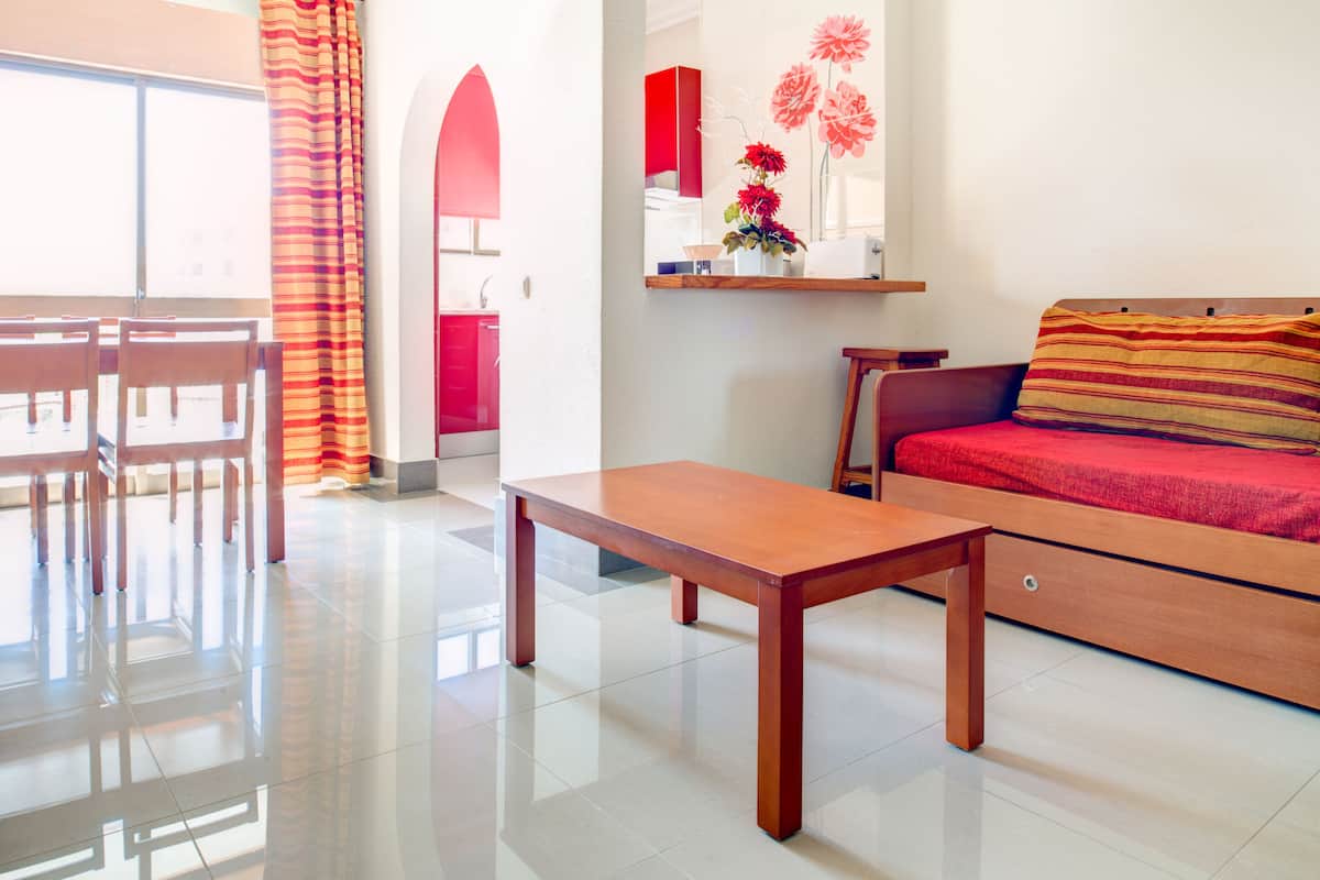 A modern living room with a sofa, a wooden coffee table, and a dining area with chairs and a table.