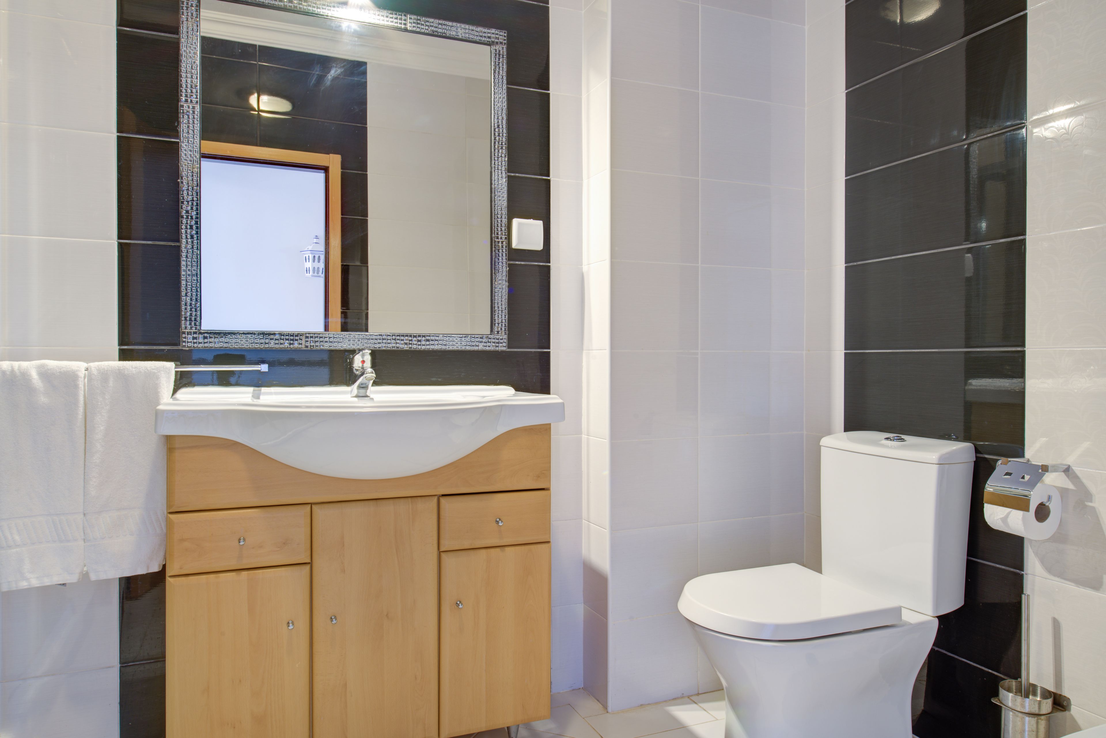 A bathroom with a white sink, wooden vanity, and a toilet.