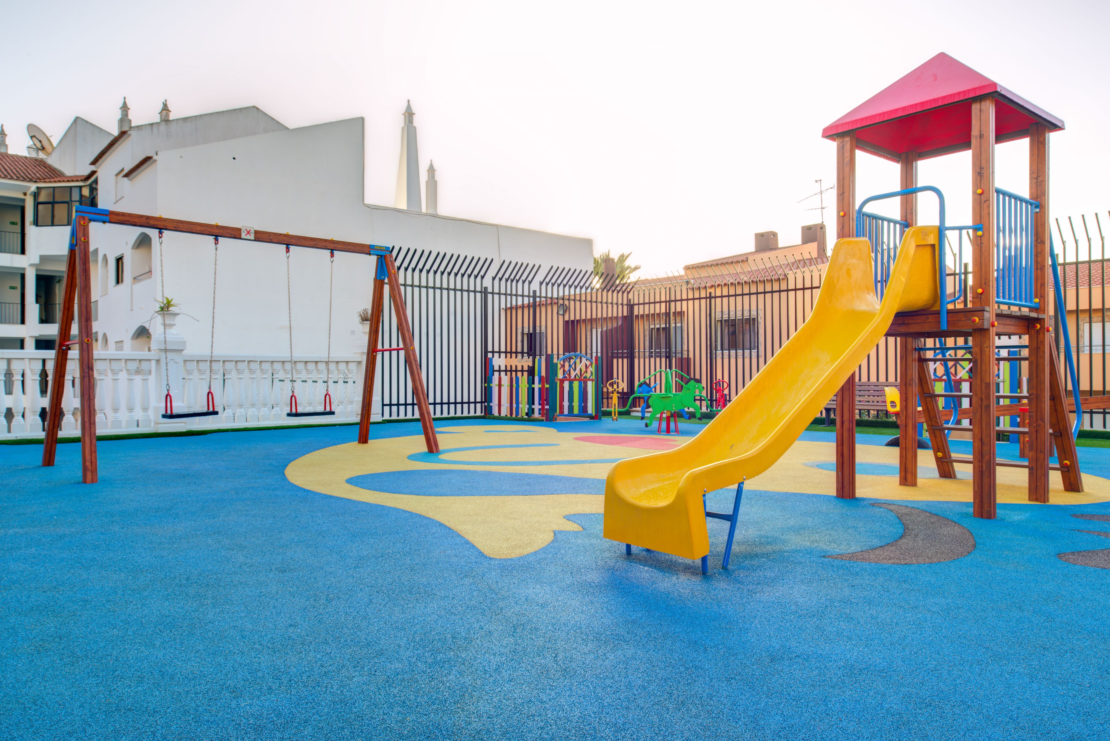 A playground with a yellow slide, swings, and a climbing structure.