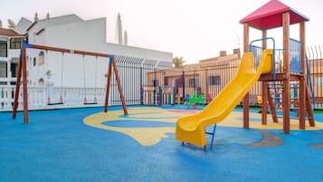 A playground with a yellow slide, swings, and a climbing structure.