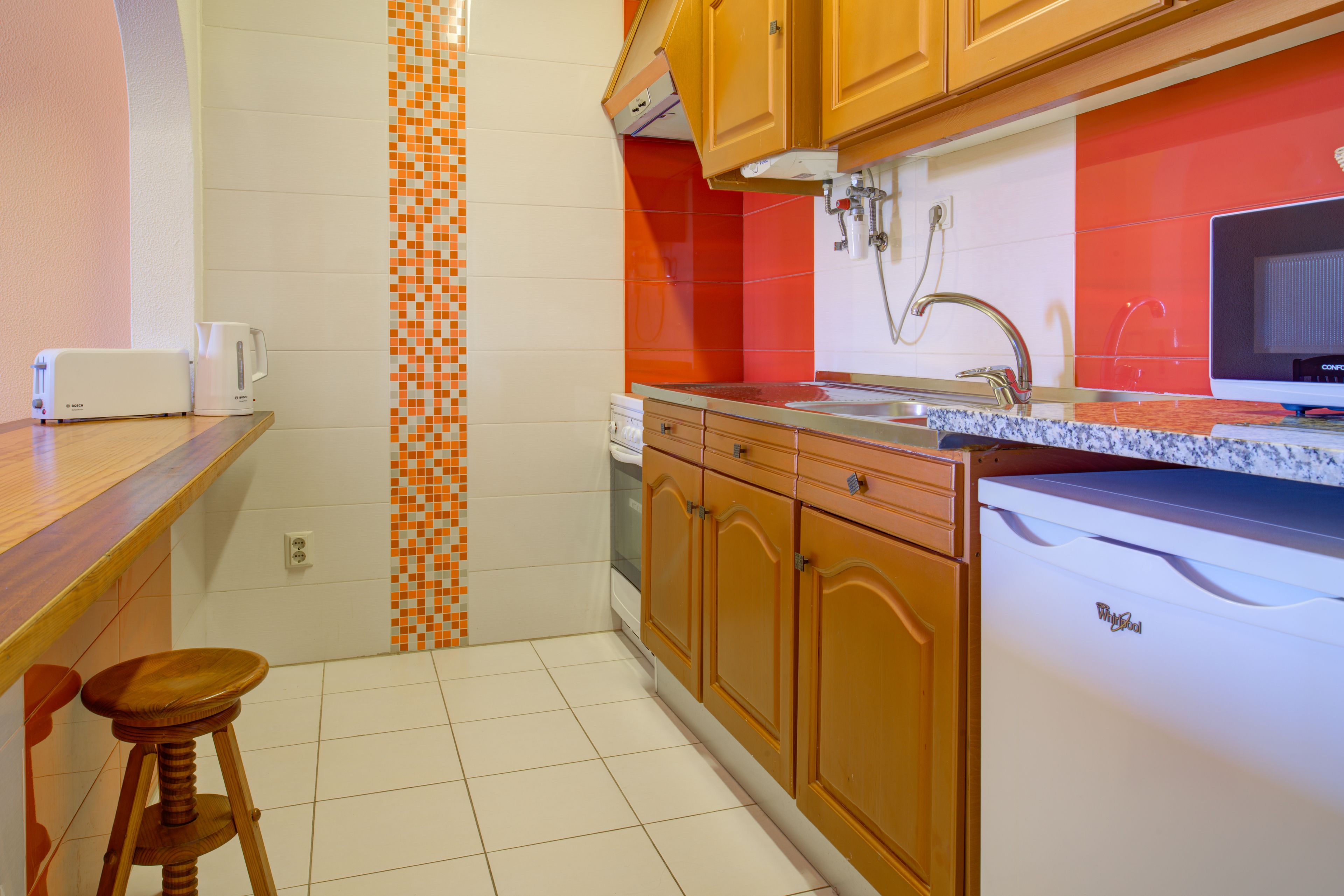Una cocina con armarios de madera, un lavamanos, una encimera y un lavavajillas.
