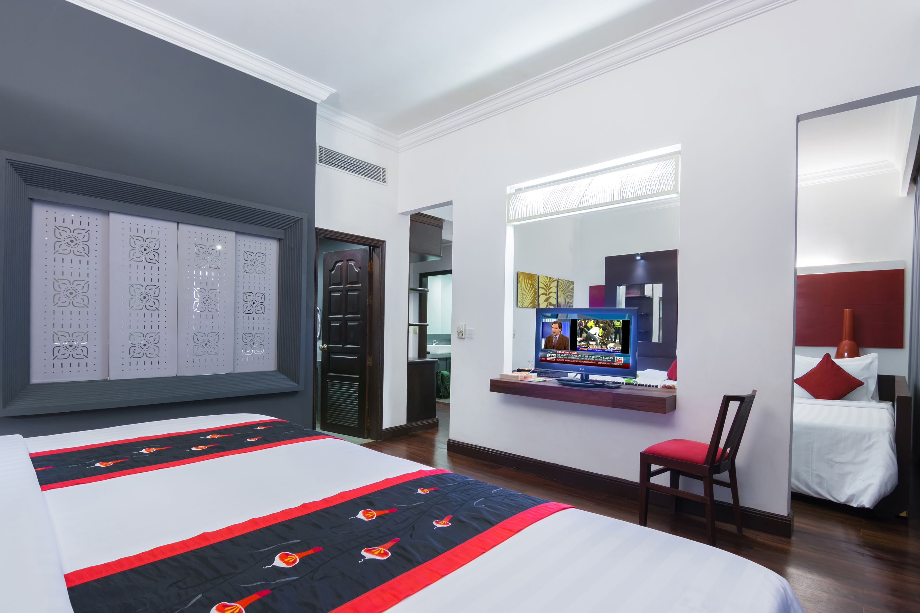 Una habitación de hotel con una cama grande, un escritorio con computadora, una silla, un televisor y un armario.