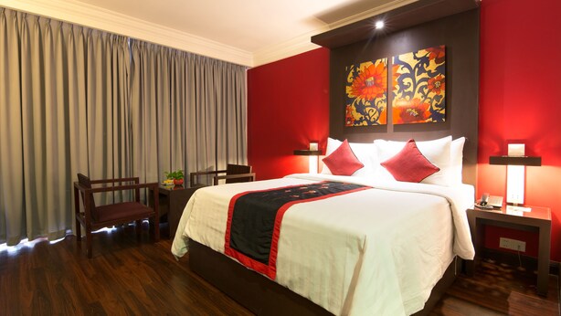A hotel room with a large bed, red walls, and a wooden floor. - Memoire d'Angkor Boutique Hotel (Siem Reap)