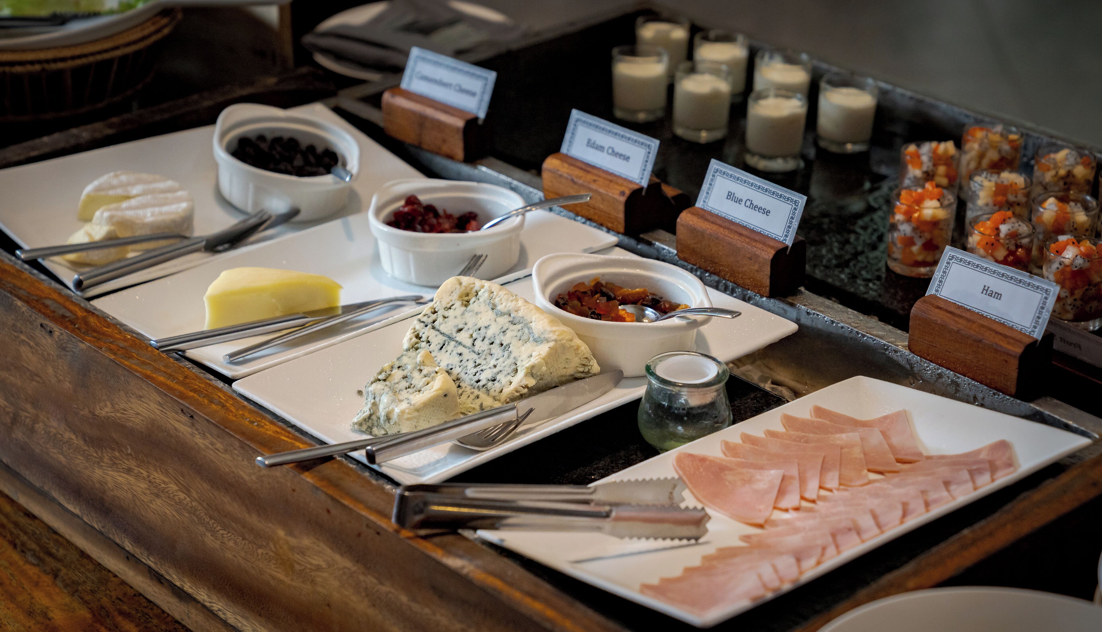 A buffet with various food items including cheese, ham, and fruits.