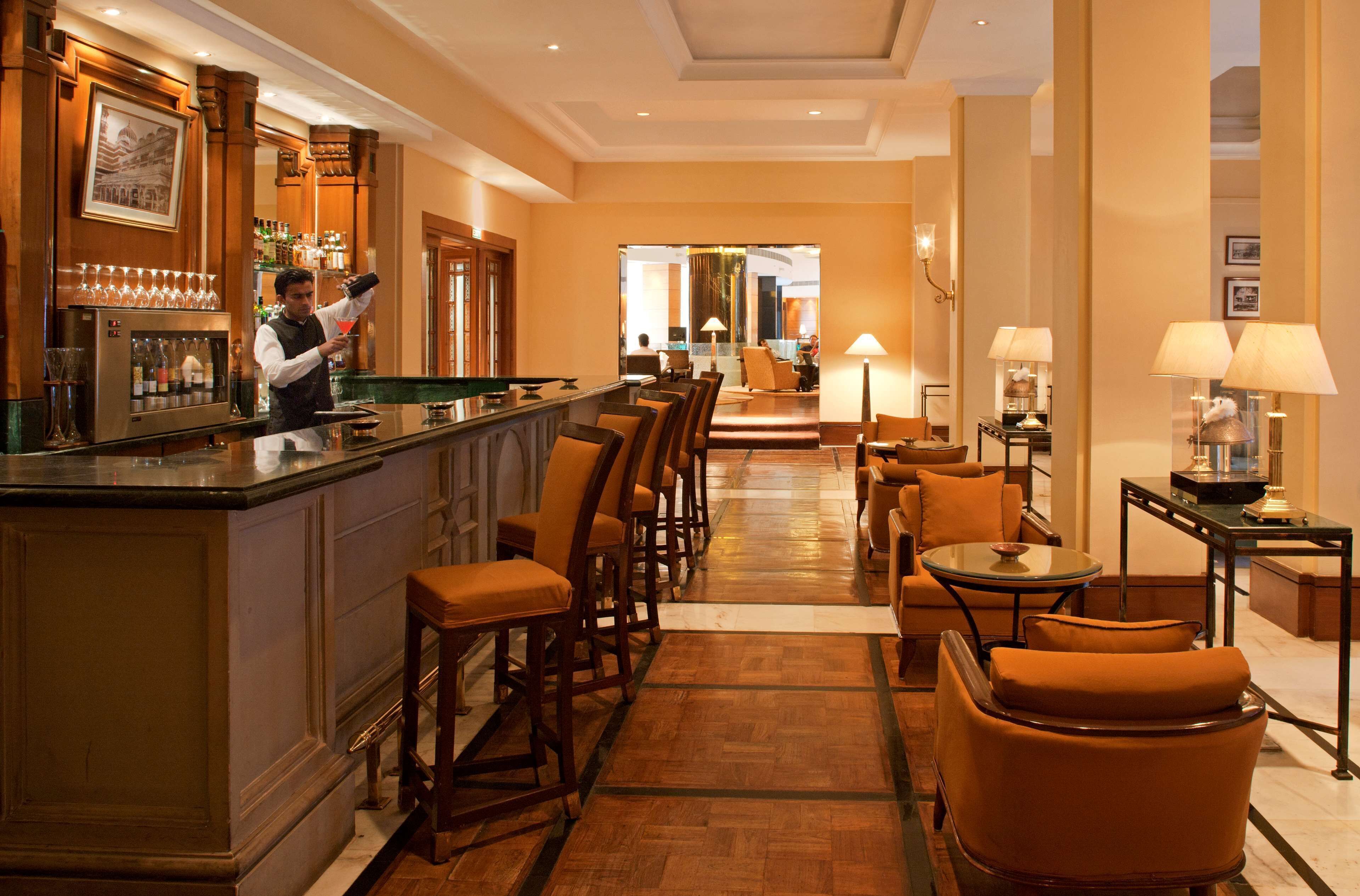 Zona de bar con camarero, barra y disposición de asientos.