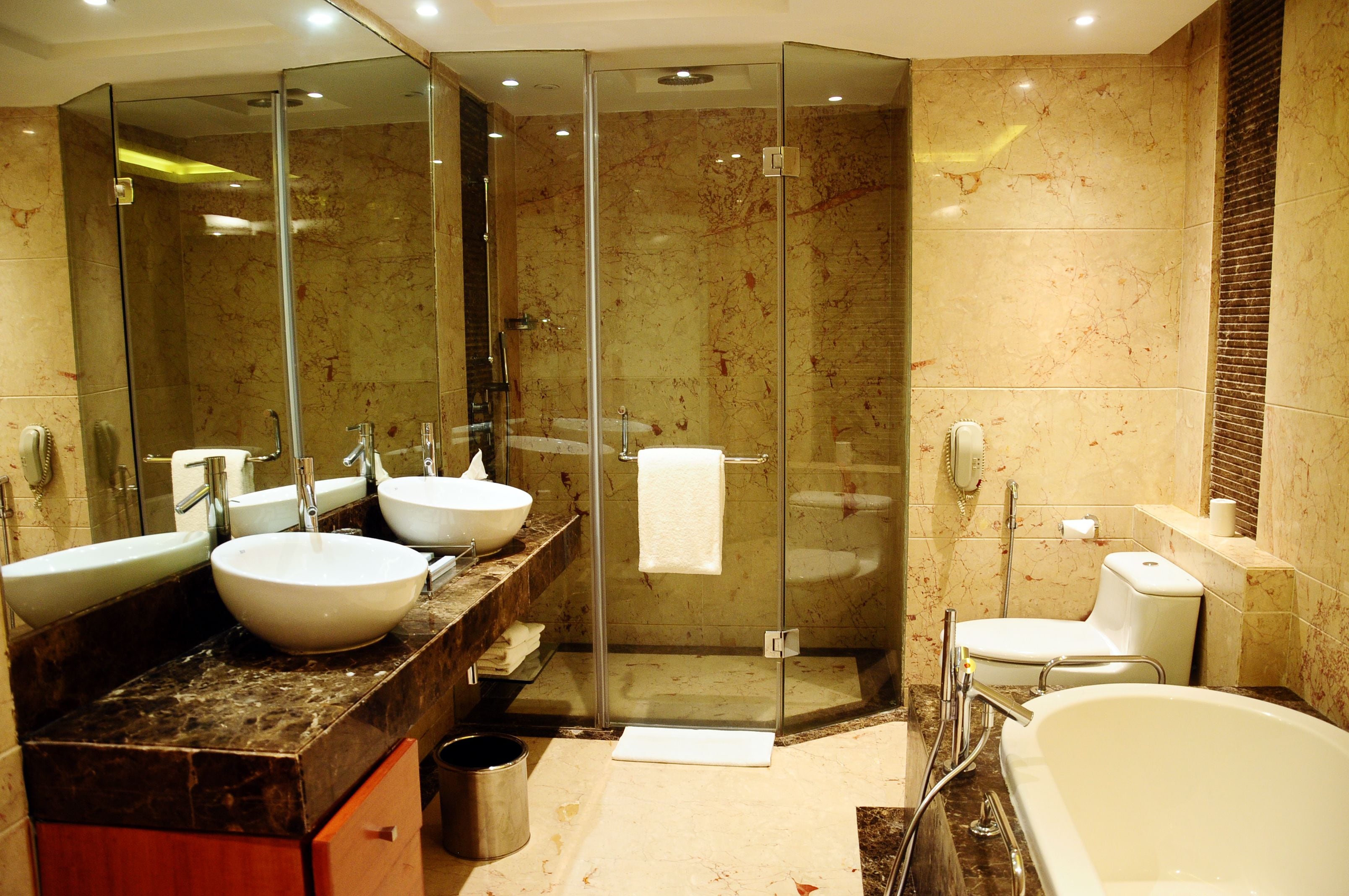 A modern bathroom with two sinks, a glass-enclosed shower, a toilet, and a bathtub.