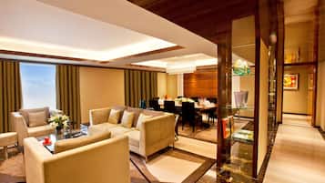 A modern hotel lobby with a seating area, a dining table, and a chandelier.