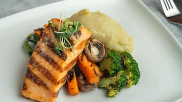 Un plato con salmón a la parrilla, puré de papas, zanahorias y brócoli.