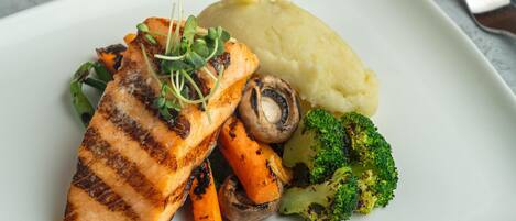 A plate with grilled salmon, mashed potatoes, carrots, and broccoli.