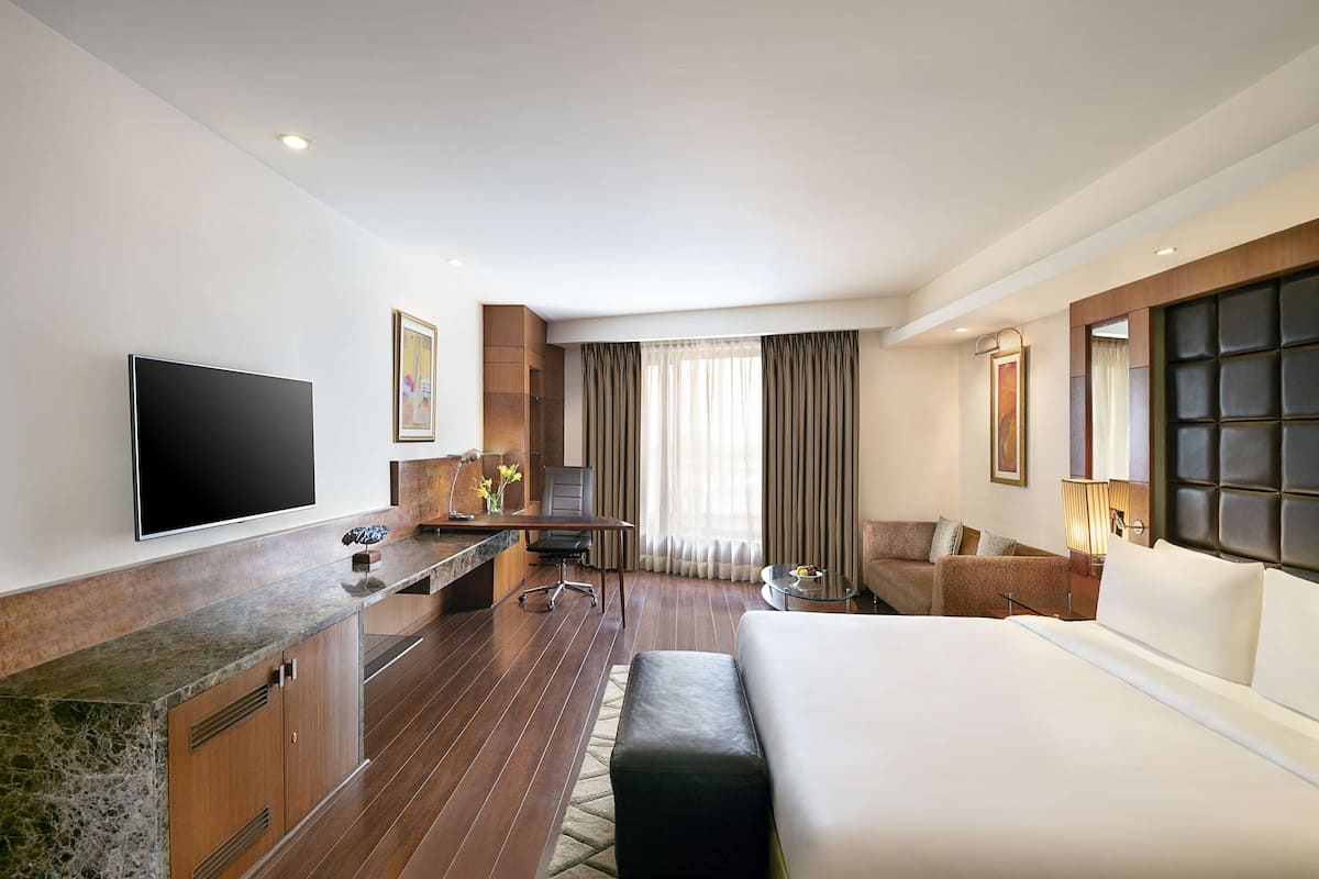 Habitación de hotel con cama, escritorio con silla, televisor y sofá.