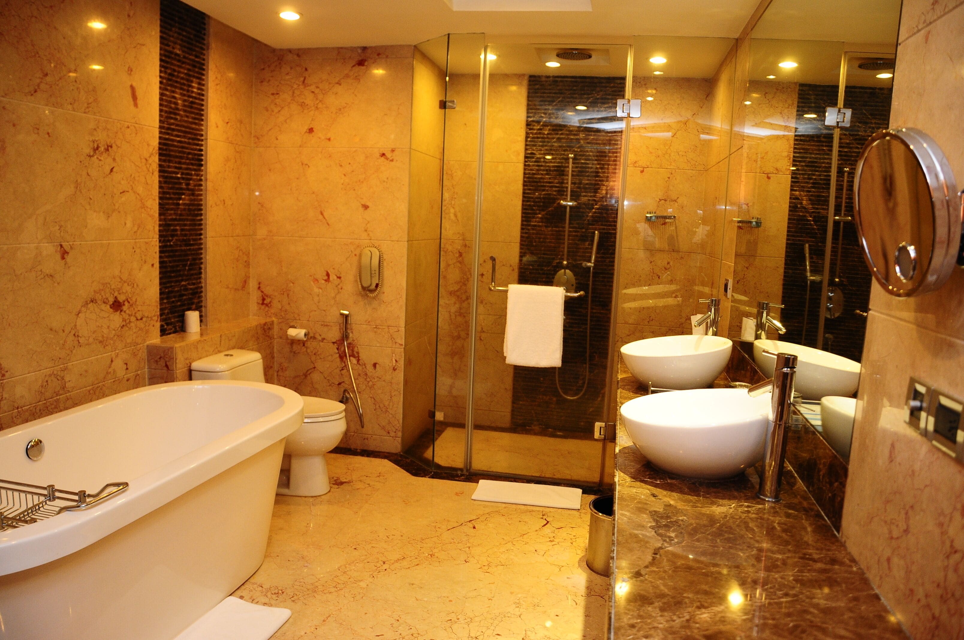 A modern bathroom with a freestanding bathtub, two sinks, a glass-enclosed shower, and a toilet.