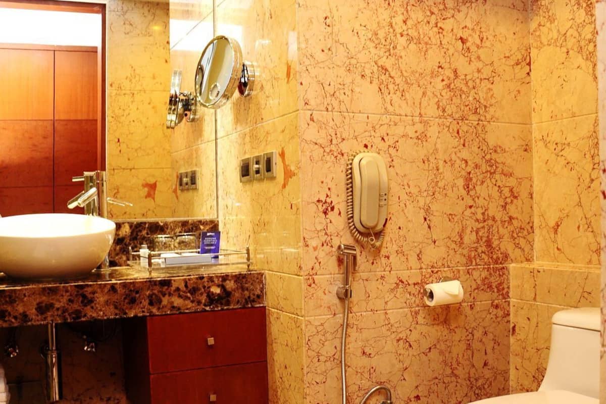 Un baño con lavamanos, espejo, toallero, inodoro y ducha.