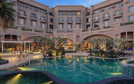 A hotel courtyard with a swimming pool, outdoor seating, and greenery.