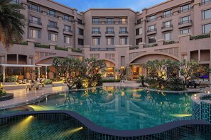 Une cour d’hôtel avec une piscine, des espaces de détente en plein air et de la verdure.
