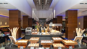 Un hall d’hôtel avec un comptoir central où sont exposées diverses pâtisseries et une machine à café.