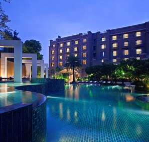 Ein Hotel mit Schwimmbad, Loungebereichen und einer modernen Fassade.