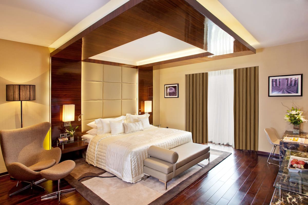 Una habitación de hotel moderna con una cama grande, un área de descanso, un escritorio y vistas a la ciudad.